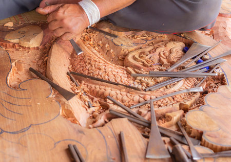 Hands of craftsman carve with a gouge in the hands on the workbench in carpentryの写真素材