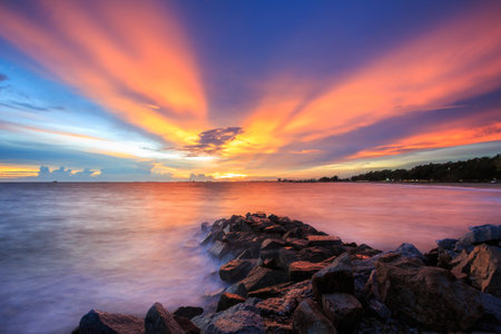 long exposure shooting of small island boat and rock in smoky sea water with blue sky, Sky burst, blurred motionの写真素材