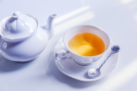 Hot tea pouring into white cup, ready to drinkの写真素材