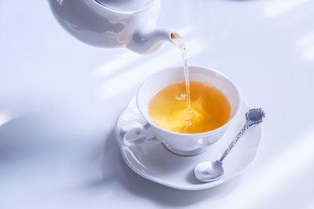 Hot tea pouring into white cup, ready to drinkの写真素材