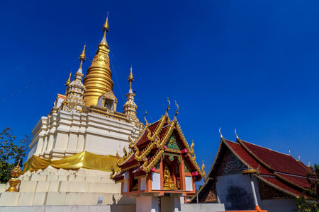 Golden light shining on white and gold pagoda during sunrise / sunset with blue sky in Mae hong son Thailandの写真素材