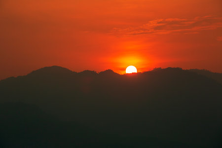 Red and orange warm sunlight in the sky during sunset with mountain  range in foreground, shade and shadow, sunset sunrise from Mae Hong Son province Thailandの写真素材