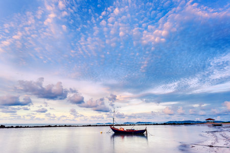Fishing boat in perfectly calm sea water like glass with the clouds in the sky, long Exposure technic taken during sunriseの写真素材