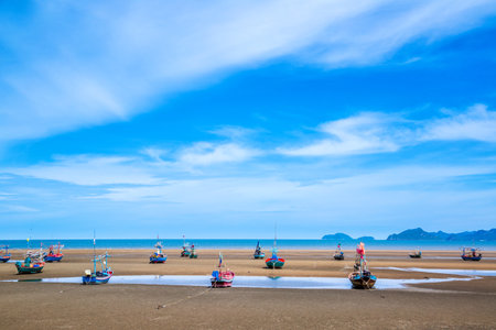 Many small fishing boats on sand beach during low tide with cloudy blue sky at Pranburi Prachuap-Kirikhan Thailandの写真素材