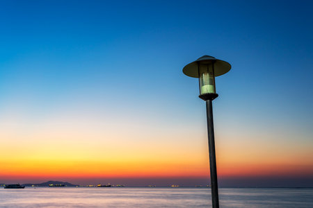 Lantern sit in front of the sky burst during sun set with smooth white sea water surfaceの写真素材