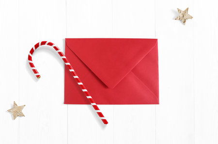 Christmas mockup scene with red envelope, candy cane decoration and stars made of birch bark on white wooden background. Empty space for your text, top view.の写真素材