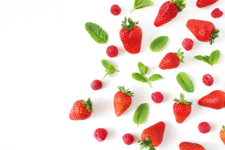 Styled stock photo. Summer healthy fruit composition with red strawberries, raspberries, fresh green mint leaves isolated on white table background. Food pattern. Empty space. Flat lay, top view.の写真素材