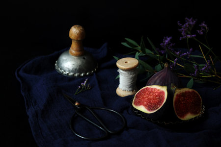 Dark still life with ripe fresh purple figs on linen tablecloth. Vintage moody composition with...
