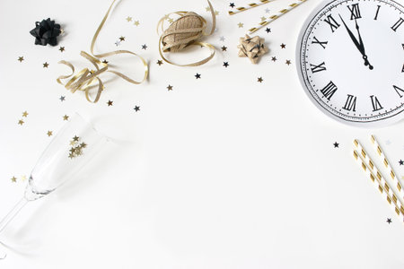 New Year still life composition with golden confetti stars, wine glass, drinking straws and clock...
