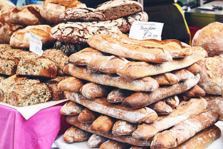 Closeup of pile of fresh French artisan sourdough baguettes and whole grain cereal and pumpkin seed...
