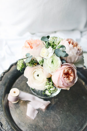 Cozy bedroom still life scene. Wedding, birthday bouquet of pink English roses, Ranunculus and...