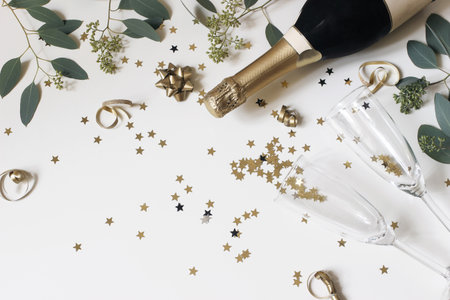 Happy New Year composition. Champagne glasses nad wine bottle with golden confetti stars and...