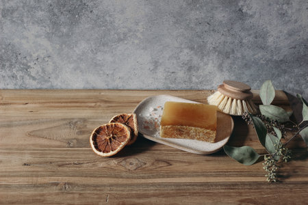 Still life of organic handmade soap bar, wooden brush and dry lemons ruit and eucalyptus on wooden...