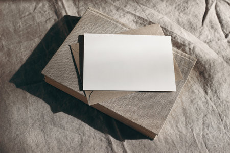 Moody stationery still life scene. Old book, blank sheet of paper, greeting card mockup and envelope...