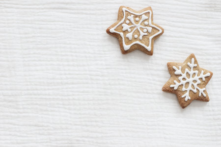 Closeup of star shaped gingerbread cookies with decorative sugar frosting. Christmas cotton muslin fabric mockups scene. Holiday background. Flat lay, top view. Festive still life.の写真素材