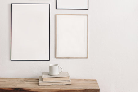 Set of black portrait picture frame mockups. Wall art gallery. Cup of coffee on pile of books on old...