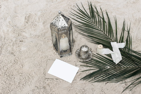 Moroccan decorative lamp, lantern. Cup of tea, coffee and green date palm leaves in sand. Muslim...