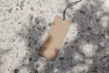 Blank craft paper gift tag, price label isolated in sunlight. Terrazzo background. Marble stone texture. Tree shadows overlay. Modern template, branding identity. Summer vacation design. Flat lay, topの写真素材