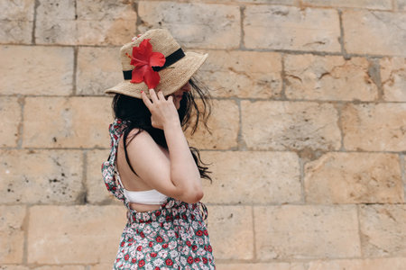 Profile of beautiful brunette model with long dark hairs, straw hat and hibiscus flower. Young woman...