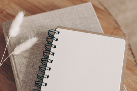 Closeup of empty diary, notepad mockup and book on wooden table. Dry Lagurus ovatus grass, blurred background. Top view. Decorative autumn office supply, lifestyle concept. Selective focus.の写真素材