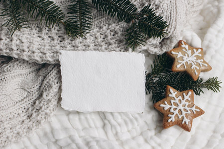 Christmas composition. Blank cotton card mockup, star shaped gingerbread cookies and fir tree branches. White muslin cotton table cloth, throw. Flatlay, top view. Winter holiday lifestyle concept.の写真素材