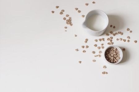 Home made breakfast still life. Crispy honey oat or buckwheat cereals isolated on white table background. Pitcher of fresh milk. Healthy snack. Vegetarian food, drink. Flat lay, top view, copy space.の写真素材