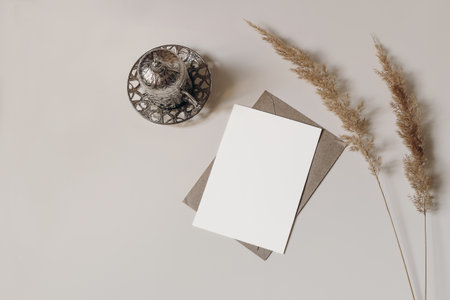 Silver Turkish decorative cup with tea. Dry grass. On beige table. Greeting card mockup for Muslim community holy month Ramadan Kareem or boho wedding. Festive background, lat lay, top view.の写真素材