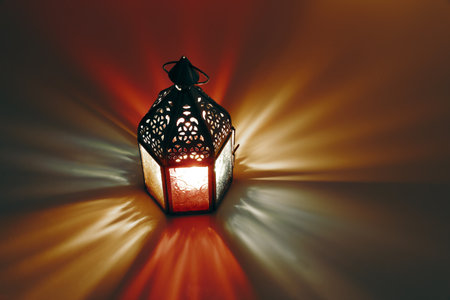 Ornamental Moroccan, Arabic lantern on the table. Burning candle at night. Colorful light rays....
