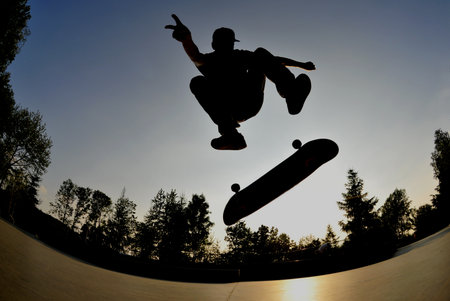 perfect silhouette of a skateboarder doing a flip trick at the skate park  の写真素材