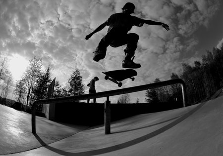 perfect silhouette of a skateboarder doing a flip trick at the skate parkの写真素材