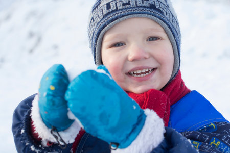 Young boy playing with a snowballの写真素材
