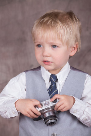 Young blond boy holding retro camera in photo studioの写真素材