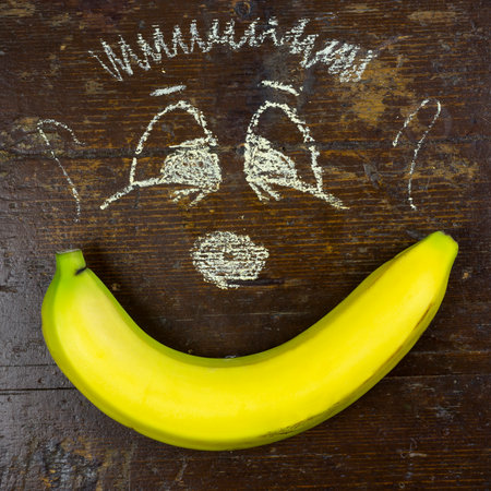Yellow fresh banana and children drawing on a wooden boardの写真素材
