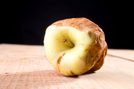 Old bitten green apple on a wooden tableの写真素材