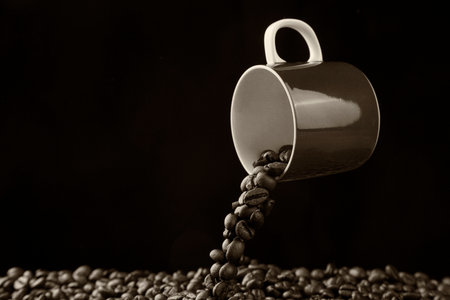 Cup with roasted coffee beans levitate above the tableの写真素材