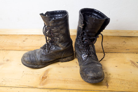 Old dirty jungle leather boots on a plank floorの写真素材