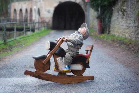 Young boy and a wooden rocking motorbike on the street, retro styleの写真素材