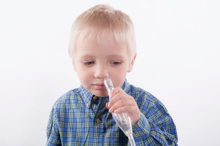 young boy using nasal aspirator, mucus suctionの写真素材