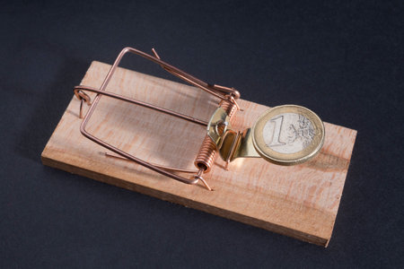 Euro coin in a wooden mousetrap, dark backgroundの写真素材