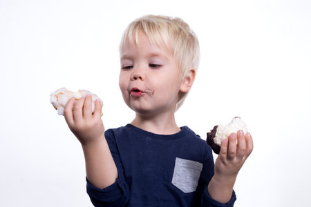 Kid eating cakes on a white backgroundの写真素材