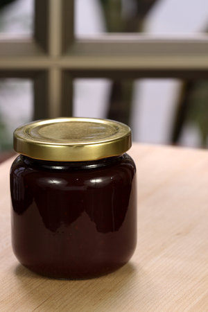 Small jar with organic homemade strawberry jam on wood preparation station