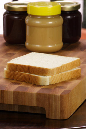 peanut butter and jelly sandwich ingredients on preparation wood board  with jars and bread 