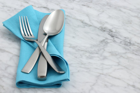 trendy and beautiful silverware set styled on linen double hemstitch napkin and antique carrara...