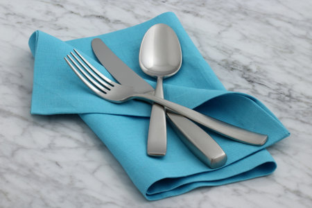 trendy and beautiful silverware set styled on linen double hemstitch napkin and antique carrara...