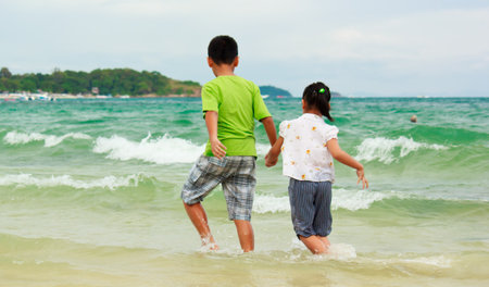 Brother and sister running along the beach in Thailand の写真素材