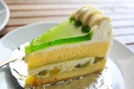 Kiwi cake on white plate with spoon の写真素材