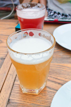 Glasses of cold beer on yellow wooden table at restaurant.の写真素材