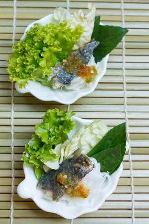 fried mackerel served with boiled thai rice vermicelli and fresh vegetable.の写真素材