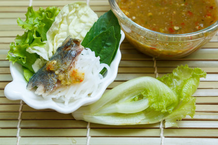 fried mackerel served with boiled thai rice vermicelli and fresh vegetable.の写真素材