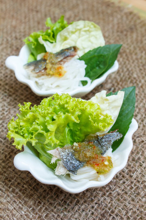 fried mackerel served with boiled thai rice vermicelli and fresh vegetable.の写真素材